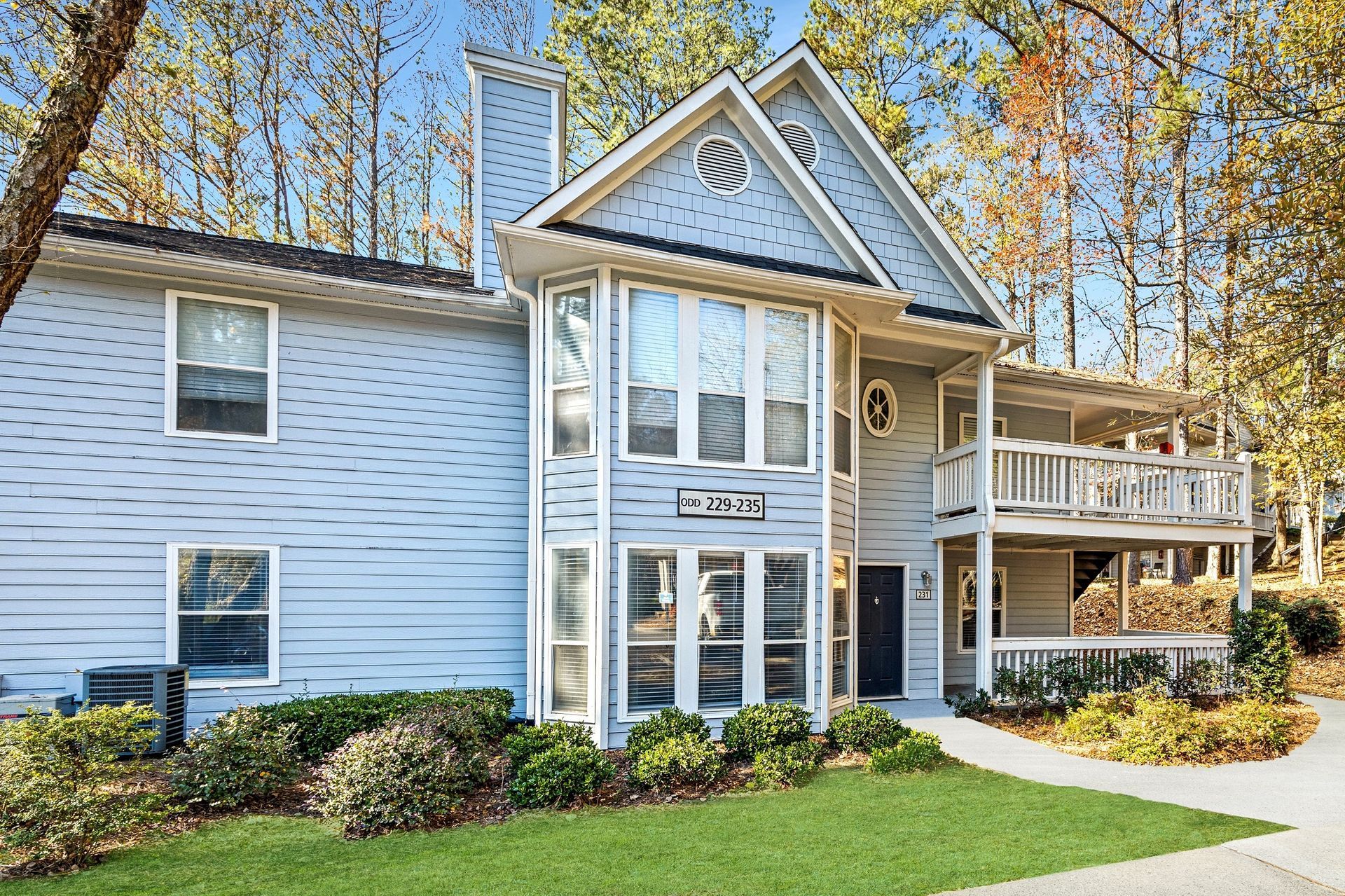 Exterior view of a multi-unit residential building with a porch and landscaped lawn.