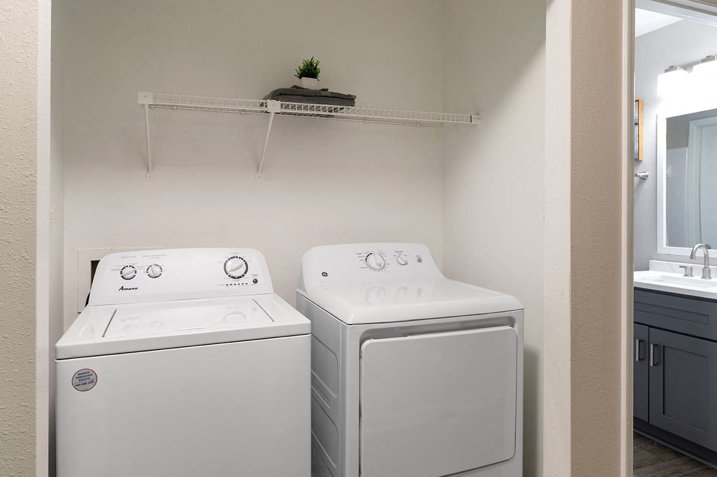 A laundry room with a washing machine and dryer next to a door leading to a bathroom.