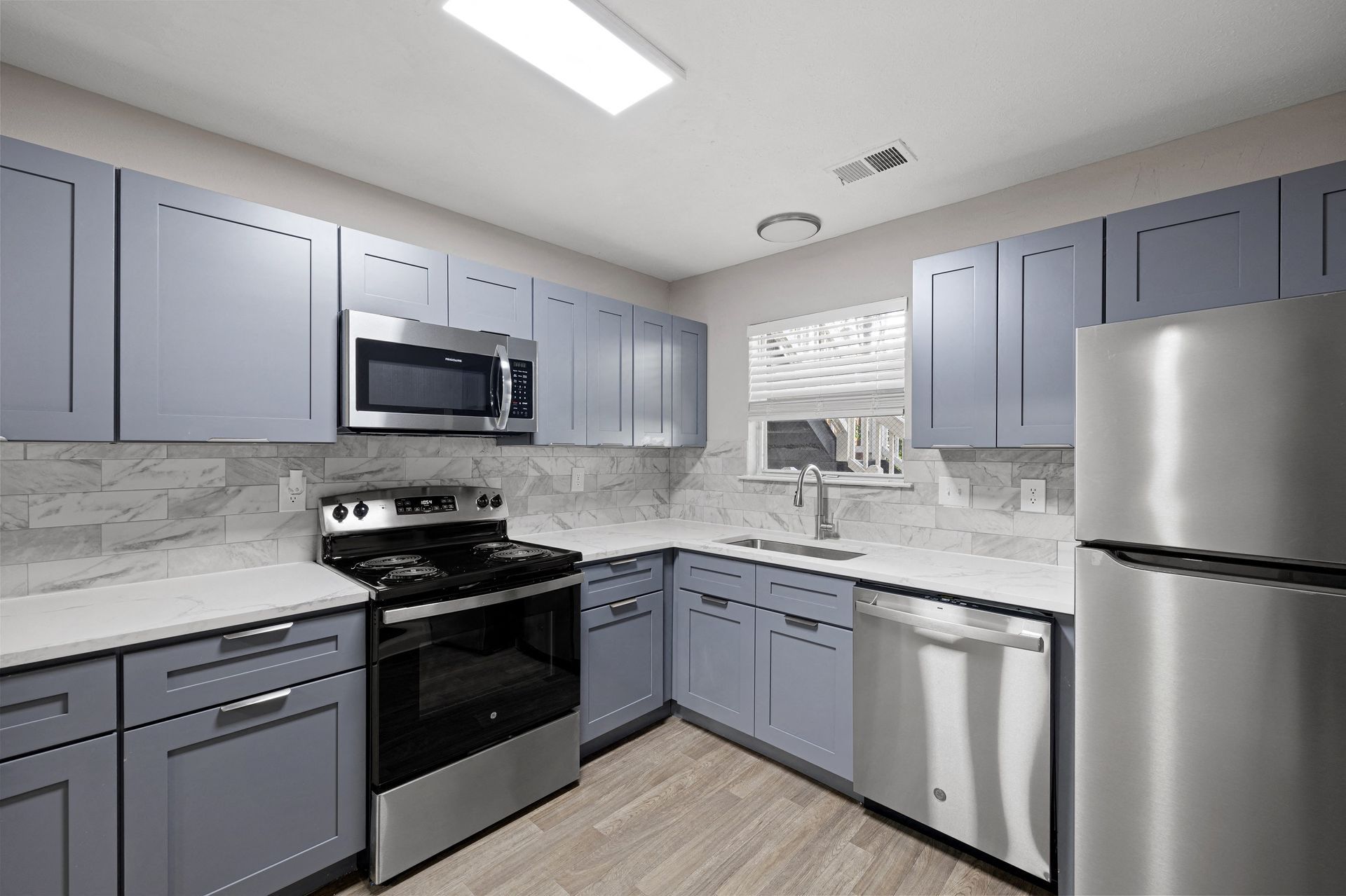 Modern kitchen featuring stainless steel appliances and blue cabinets.