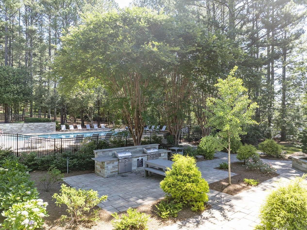 Outdoor community space with a pool, barbecue area, and greenery.