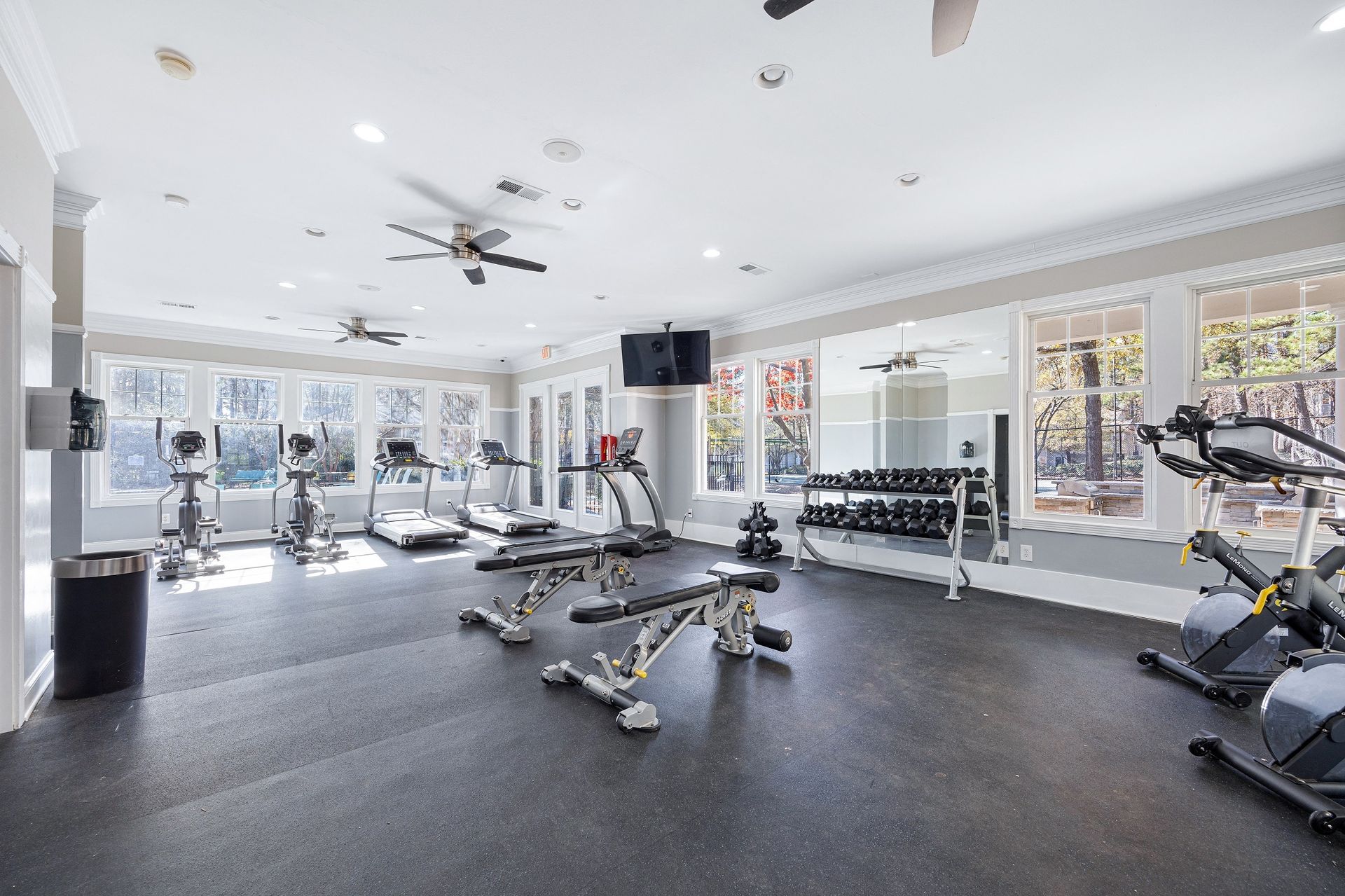 Modern fitness center with exercise equipment and large windows.