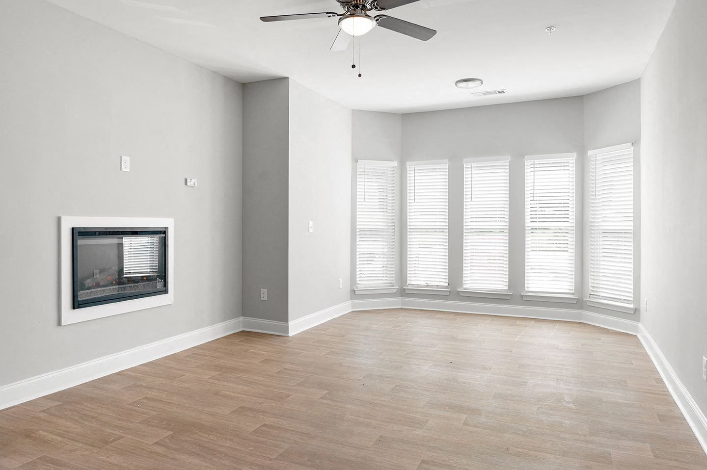 Bright and spacious living room with a ceiling fan and large windows.