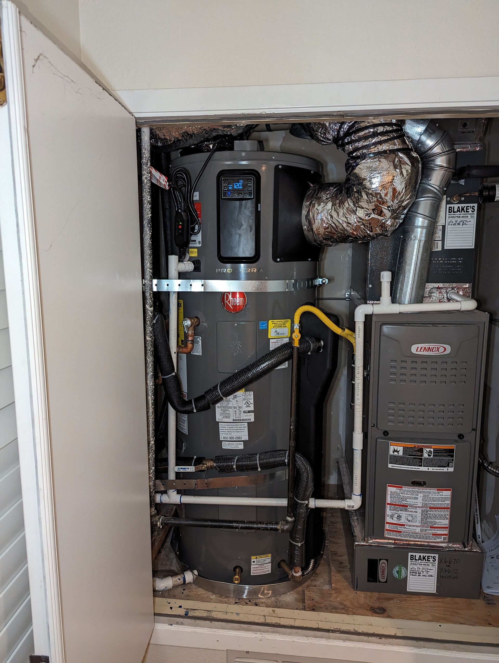 A utility closet containing a water heater and a Lennox furnace with vent pipes. The space is a mix of metal, pipes, and wires.