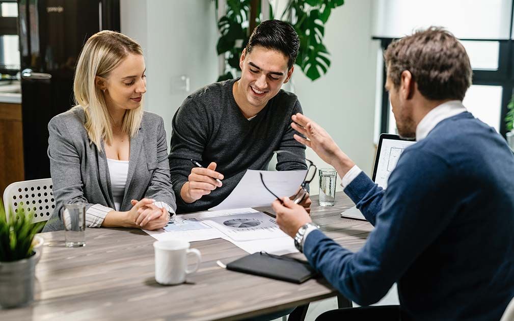 A couple reviews documents with a professional in an office setting.