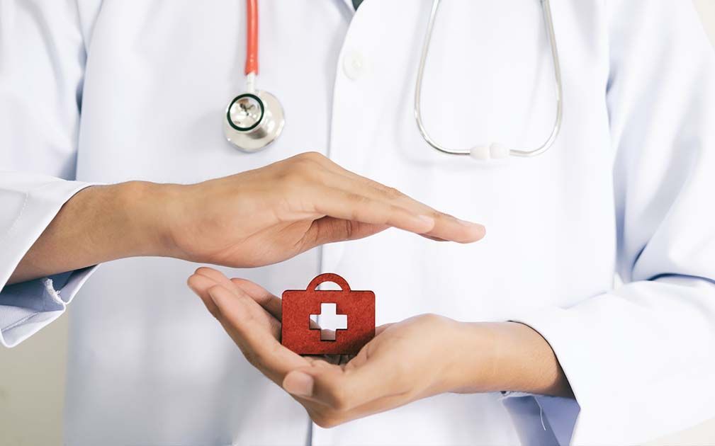 Doctor holding a red medical kit icon, hands protecting it, stethoscope visible.