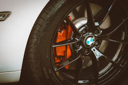 A close up of a bmw wheel with orange brake calipers.
