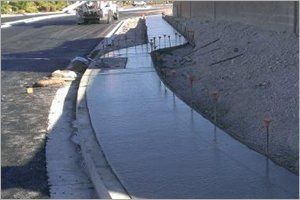 Curb and gutter being constructed alongside a road with concrete and rebar supports.