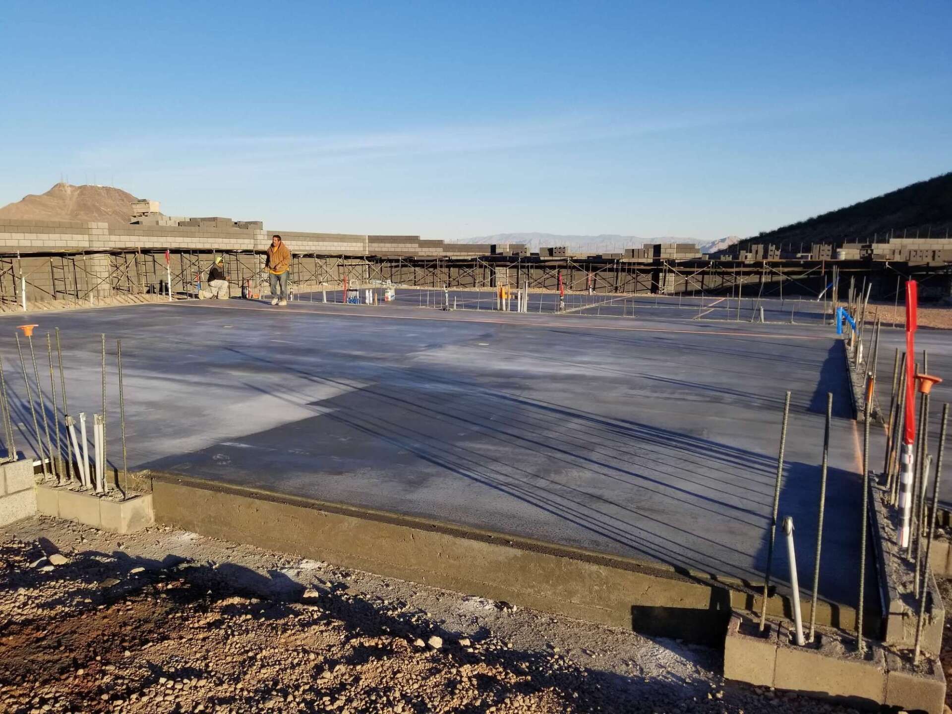 Concrete slab construction site with pipes and mountain background.