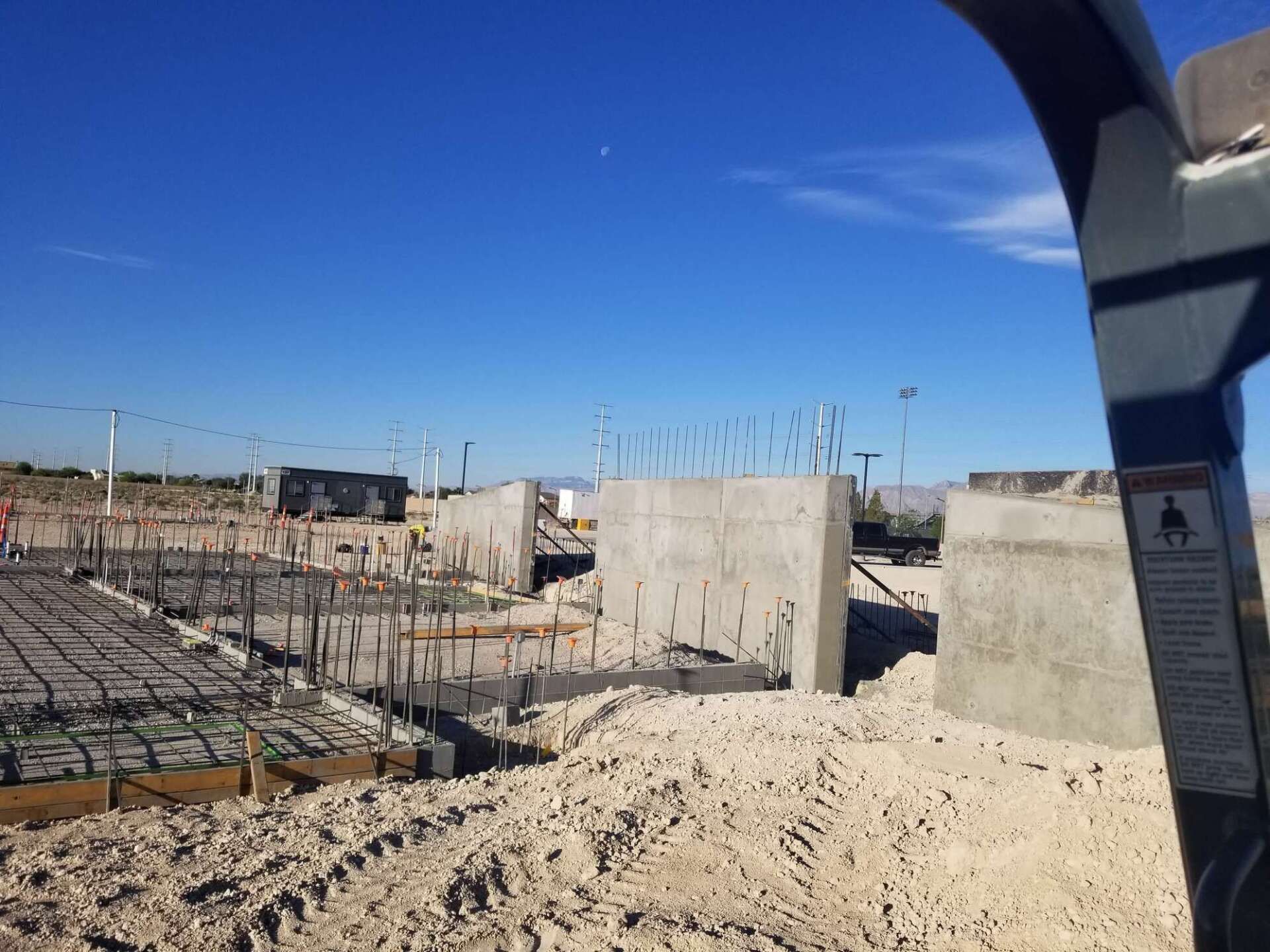 Construction site with concrete forms and rebar under a blue sky.