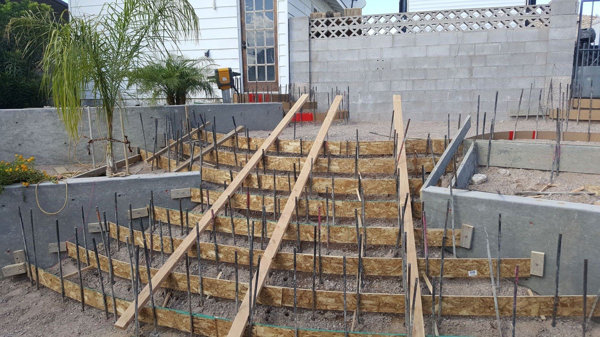Wooden forms for concrete steps under construction outdoors. Gray concrete walls surround the step area.