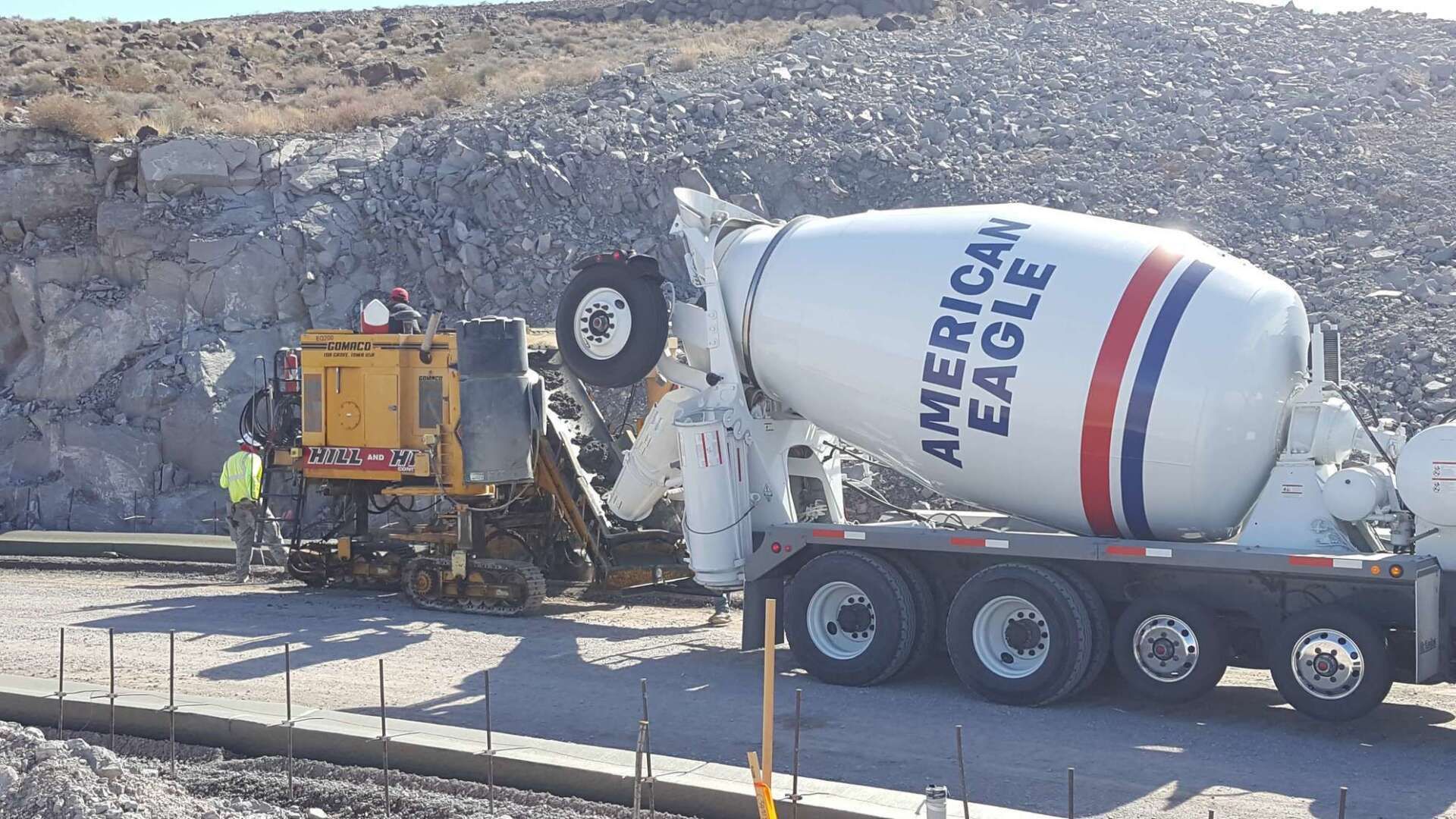 A cement truck pours concrete into a machine on a construction site.
