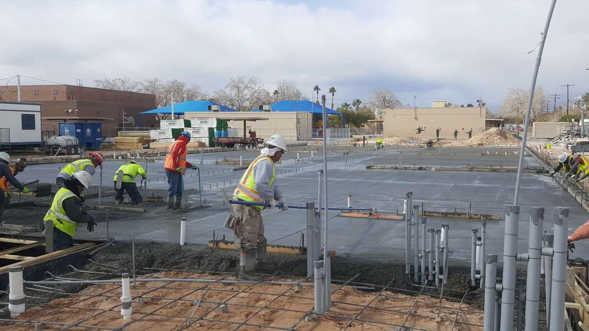 Construction workers smoothing wet concrete at a construction site outdoors.