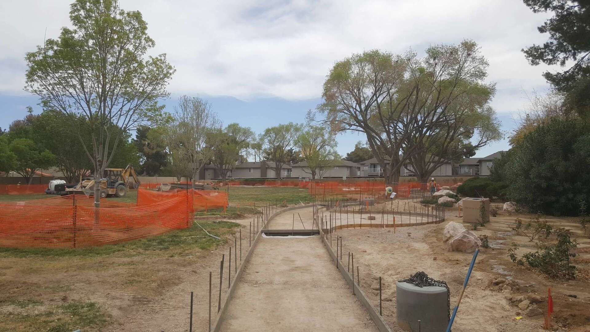 Construction site with a pathway being built; orange fencing surrounds the area.