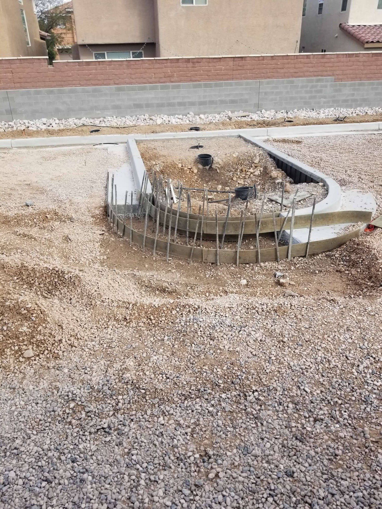 Concrete utility box with protruding metal rods, surrounded by gravel on a rooftop, with buildings in the background.