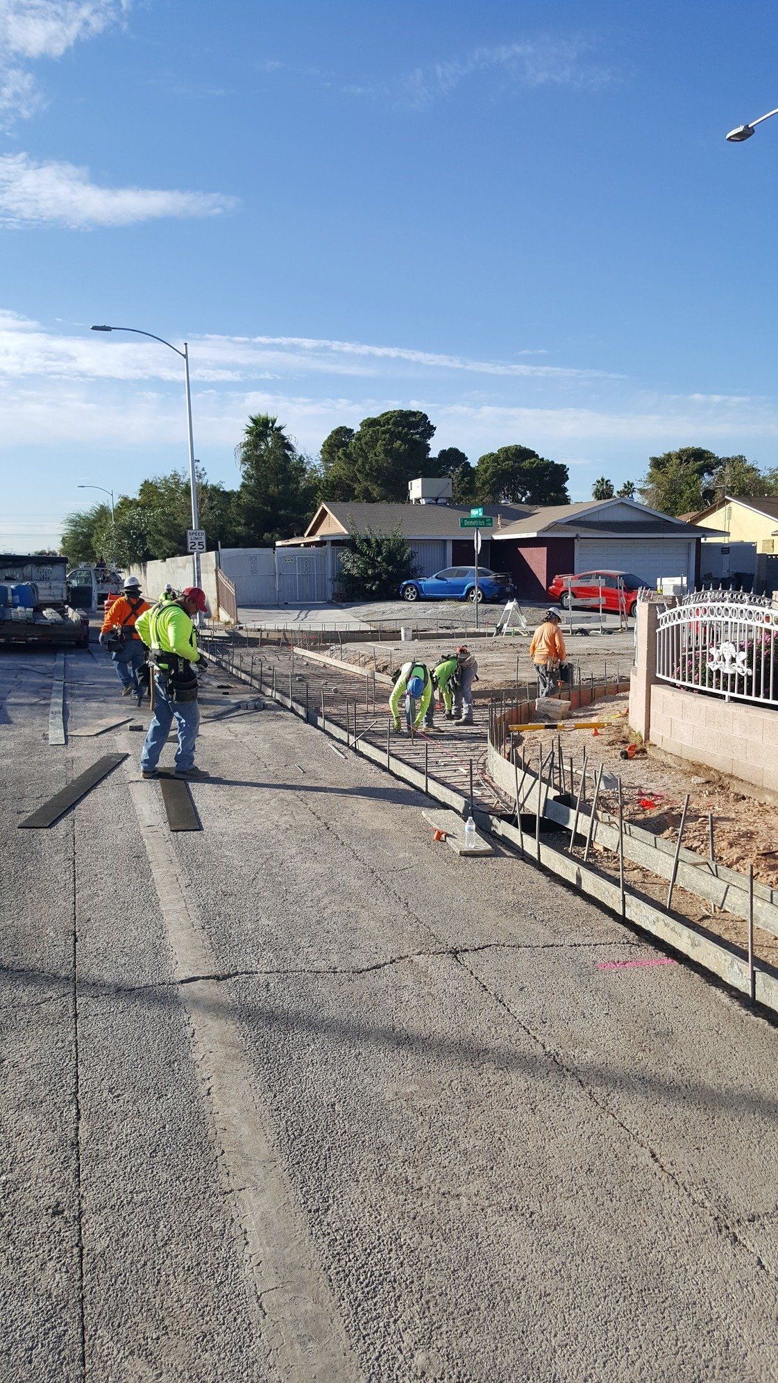 Construction workers pouring concrete on a roadway on a sunny day.