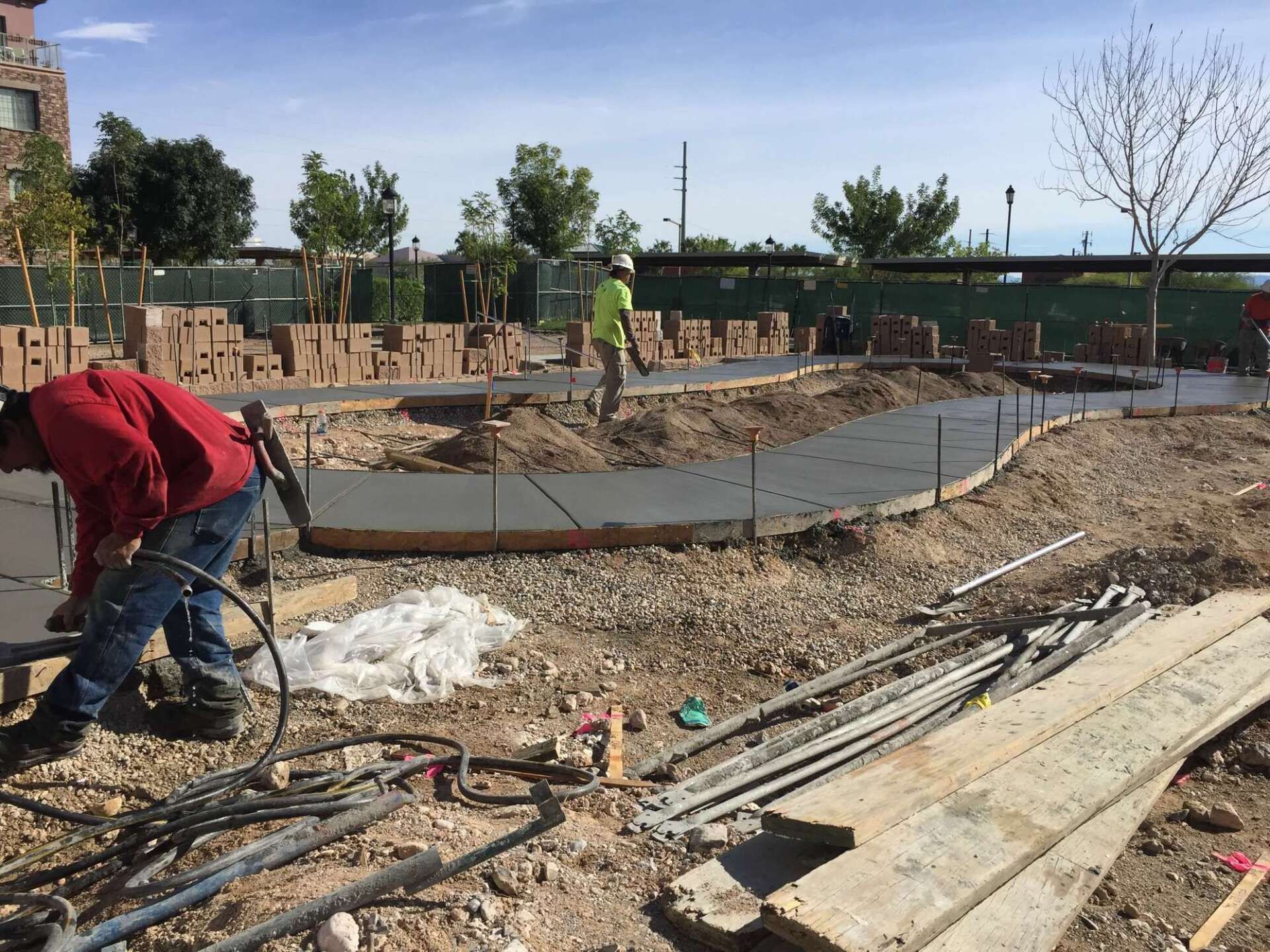 Construction workers pouring concrete for a pathway in an outdoor setting.