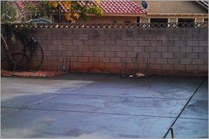 Concrete patio in front of a brick wall, with a residential area in the background.
