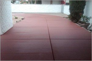 Red concrete driveway, leading to a house.