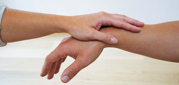 Une main repose sur le poignet d'une autre, probablement pour un examen médical.