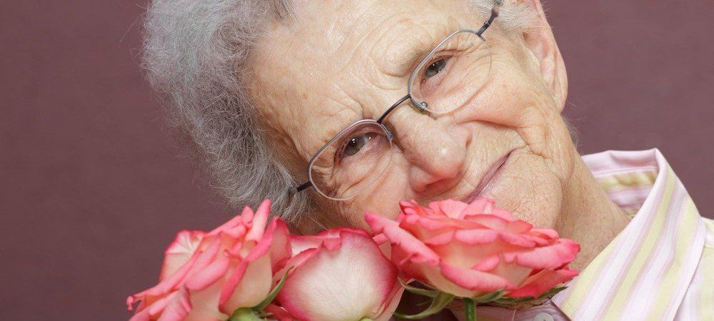 Elderly woman smelling roses in Artesia, CA.