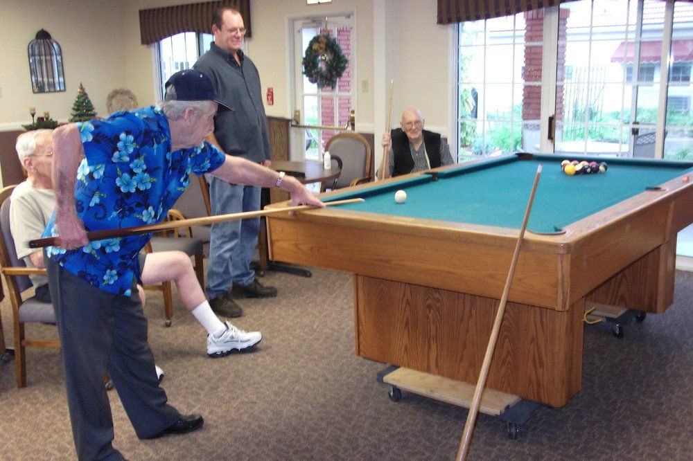 Elderly gentlemen play pool.