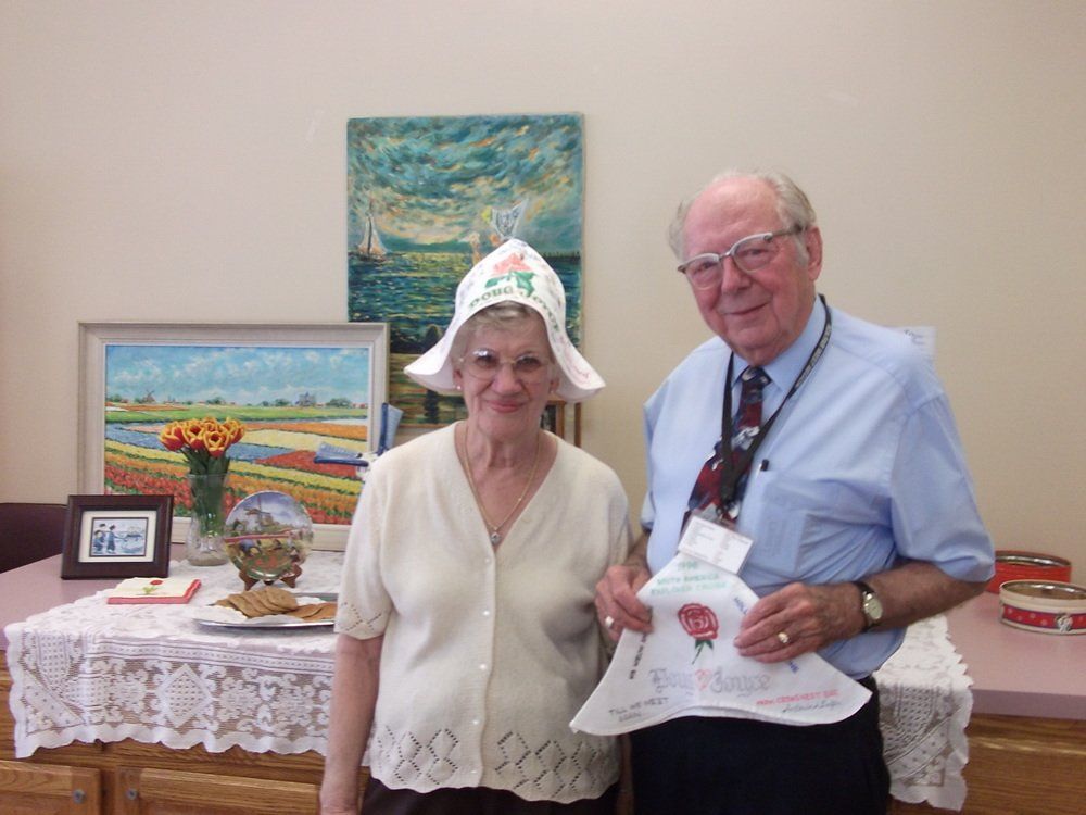 An elderly man and women. The woman wear a festive hat.