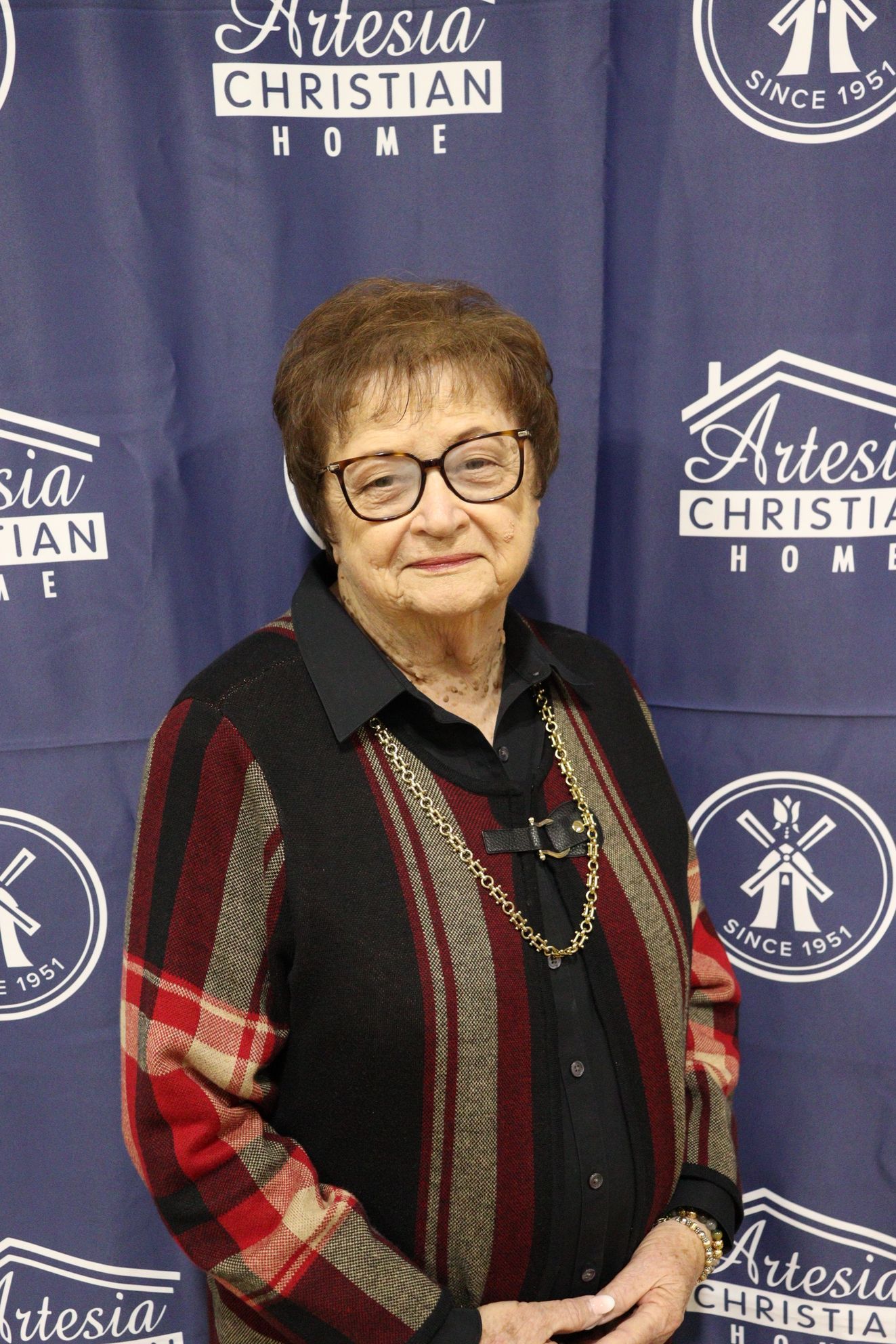 Smiling older man in a patterned shirt, standing in front of a backdrop with a Christian Home logo.
