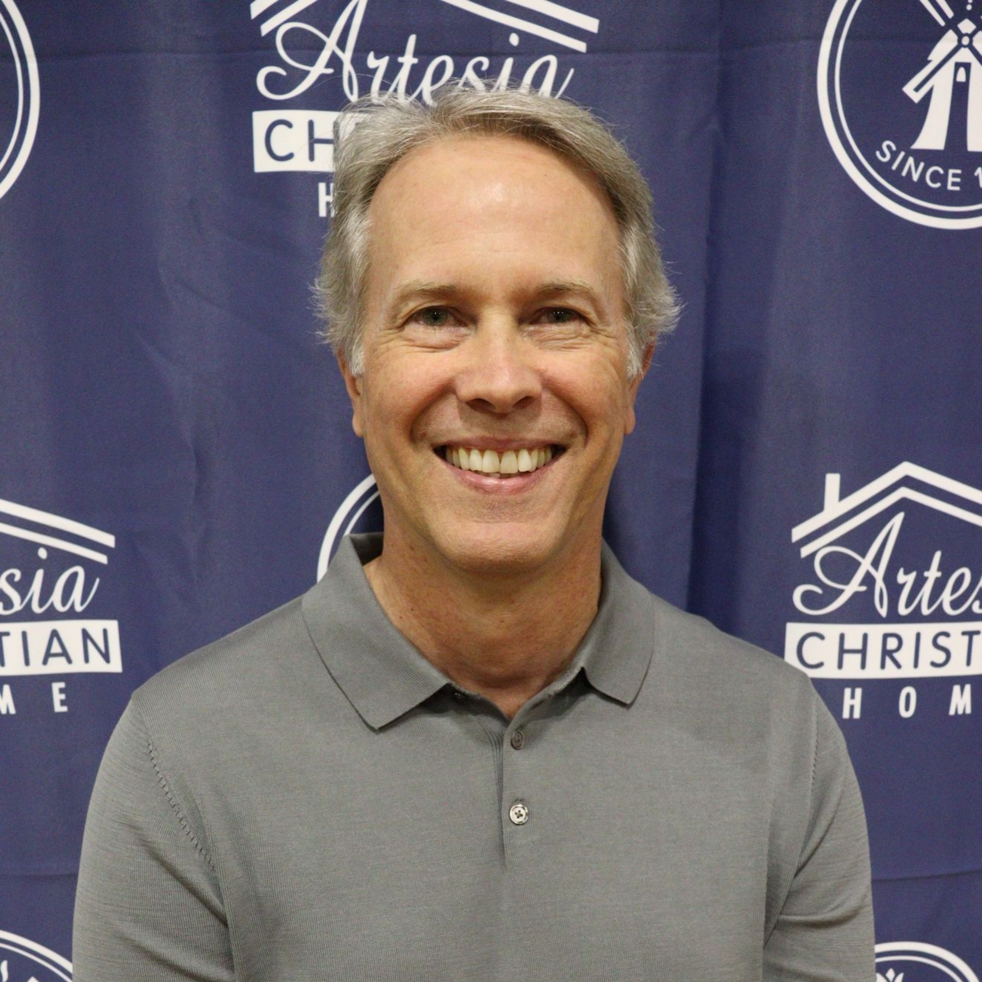 Silhouette of a person in a suit and tie. Grey face, black hair and suit.