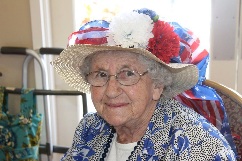 Elderly woman wearing festive hat, smiling, indoors.