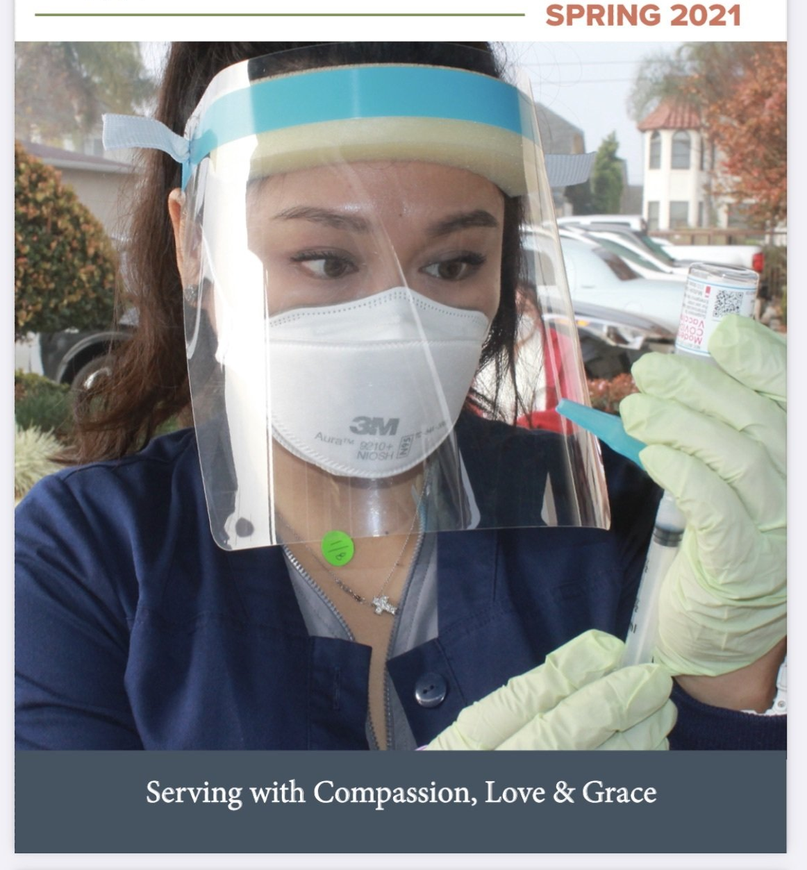 Nurse in PPE preparing syringe for vaccine, outdoor setting. Spring 2021.