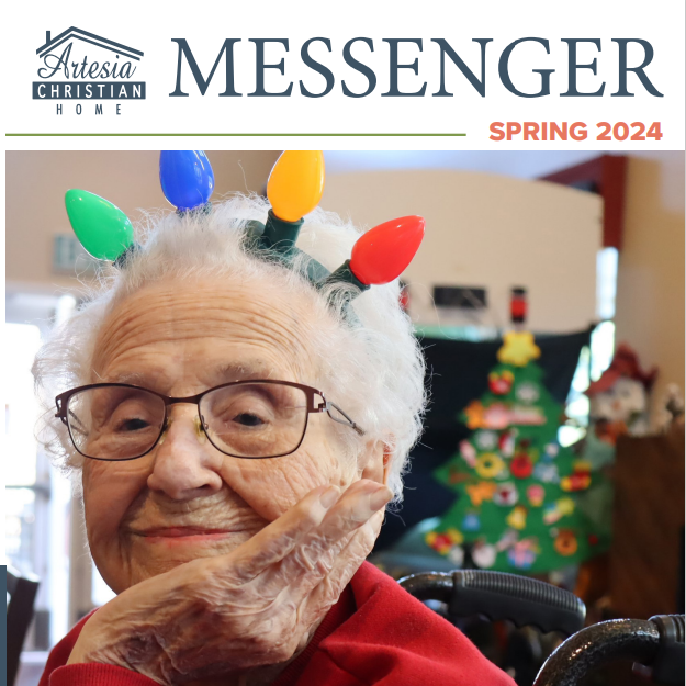 Cover of Artesia Christian Home Messenger. Elderly woman wearing light-bulb headband, smiling, in front of a Christmas tree.