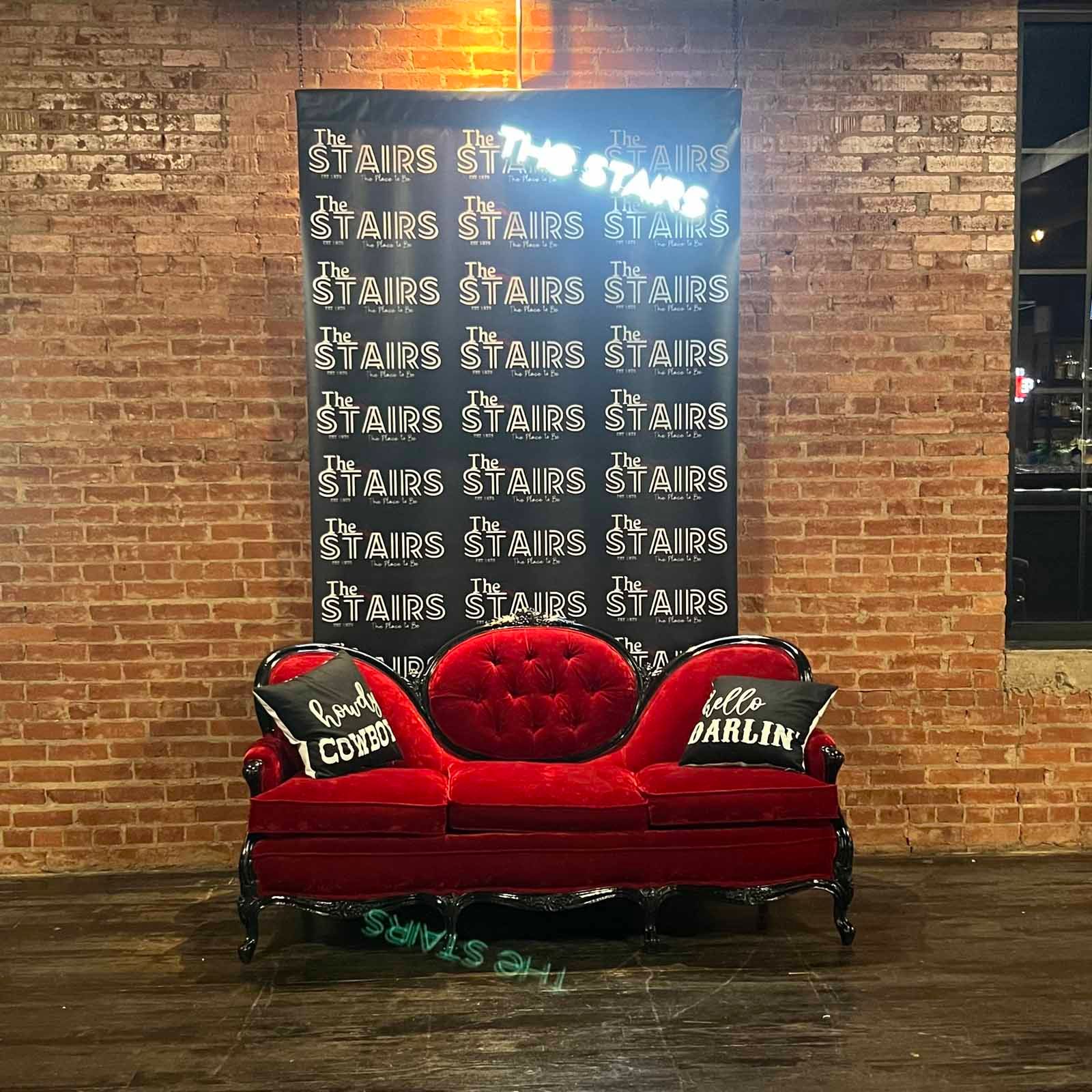 A red couch in front of a sign that says stairs