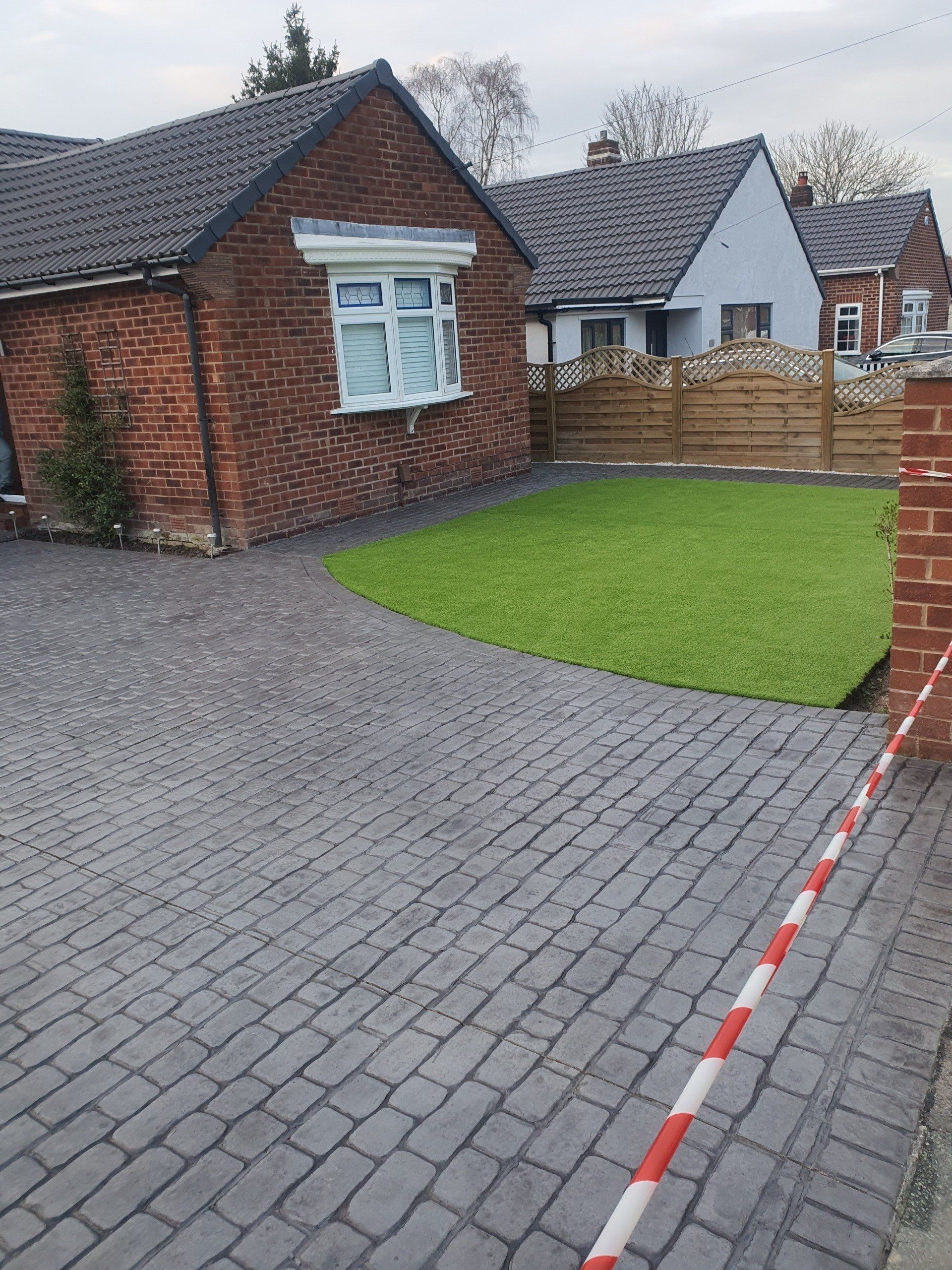 Brick house with cobblestone driveway and green lawn.