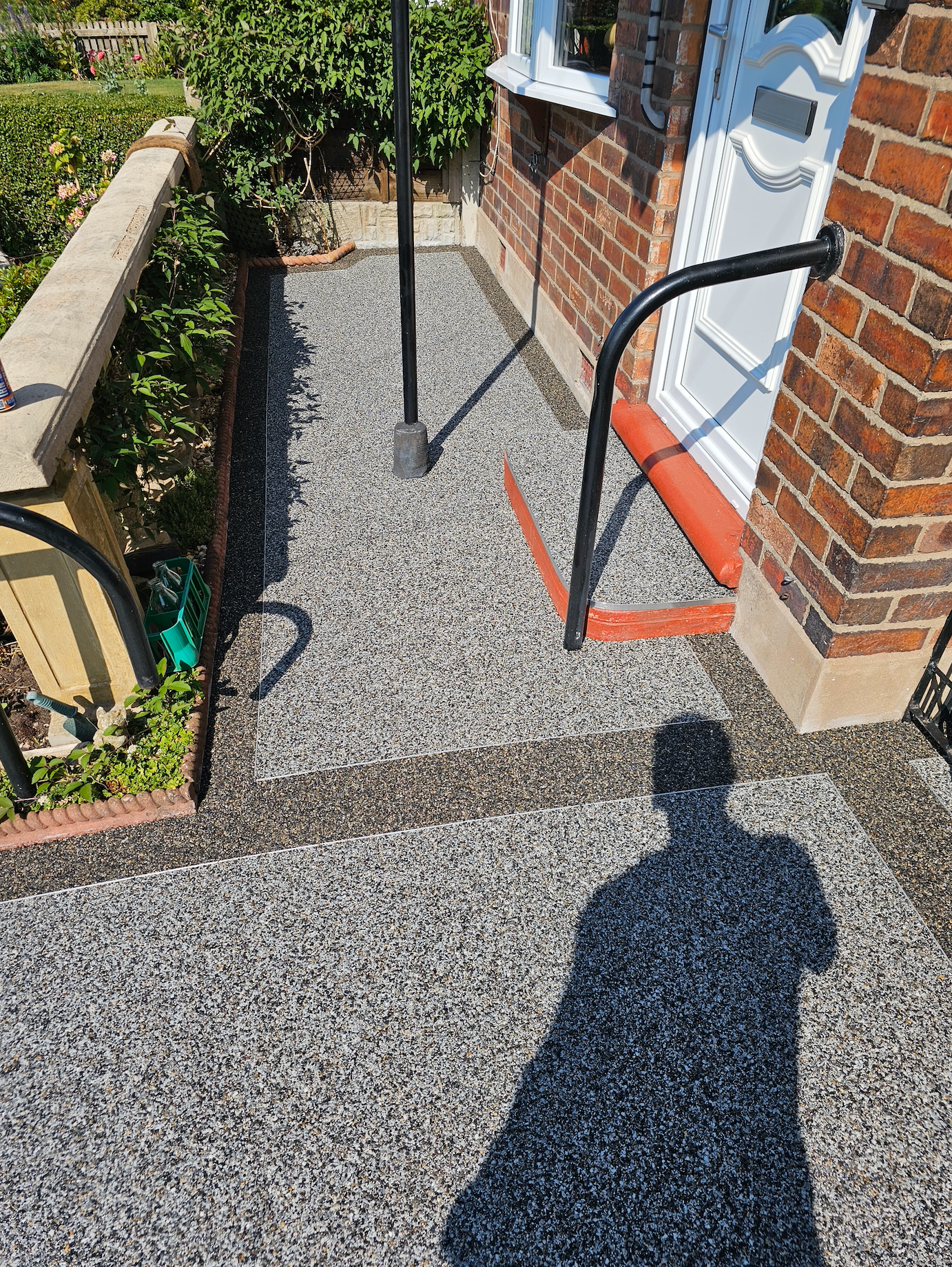 Gravel pathway leading to a doorway. A person's shadow is cast on the path.