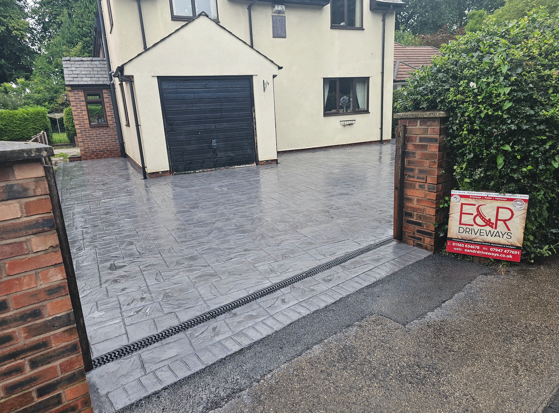 A house with a newly paved gray driveway. A sign for a contractor is visible.