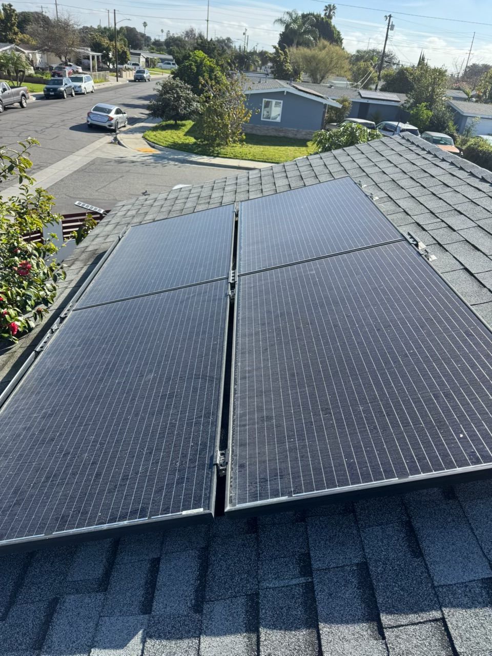Solar panels on a rooftop overlooking a residential street on a sunny day