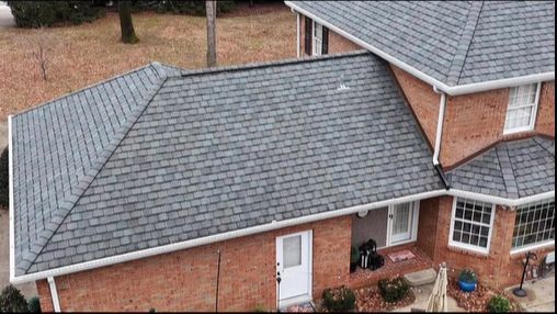 An aerial view of a brick house with a gray roof.