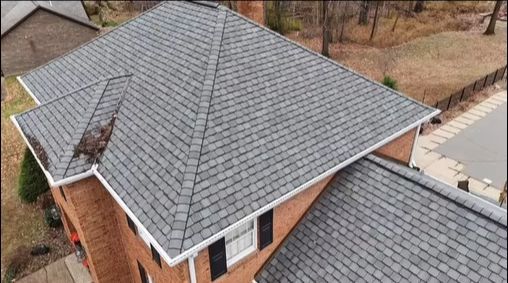 An aerial view of a brick house with a gray roof.