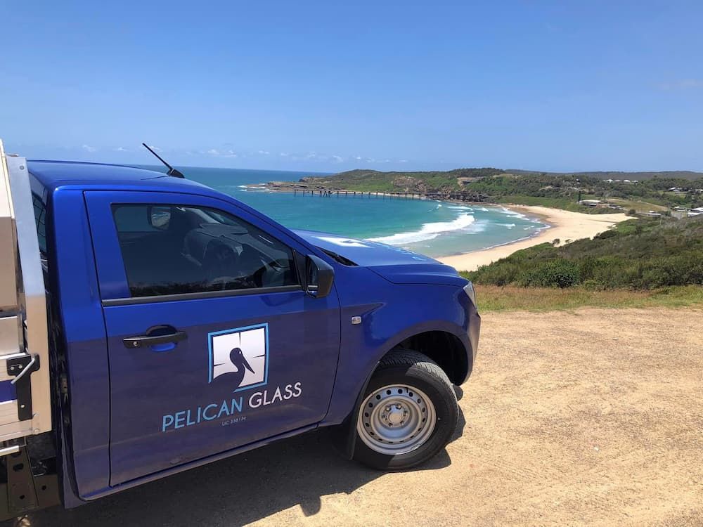 A Blue Pelican Glass Car Parked On The Seaside — Pelican Glass in Lake Macquarie, NSW