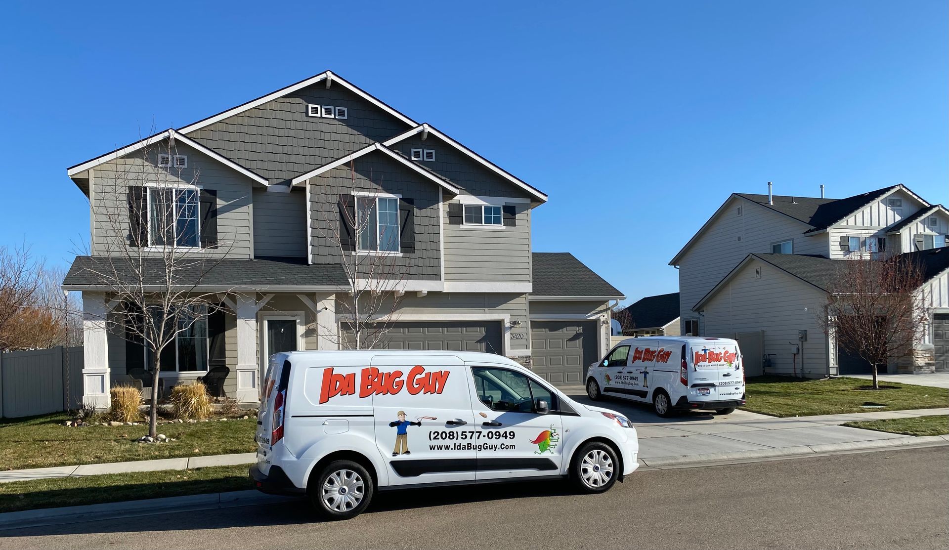 two Ida Bug Guy Pest Exterminator vans are parked in front of a large  Boise house