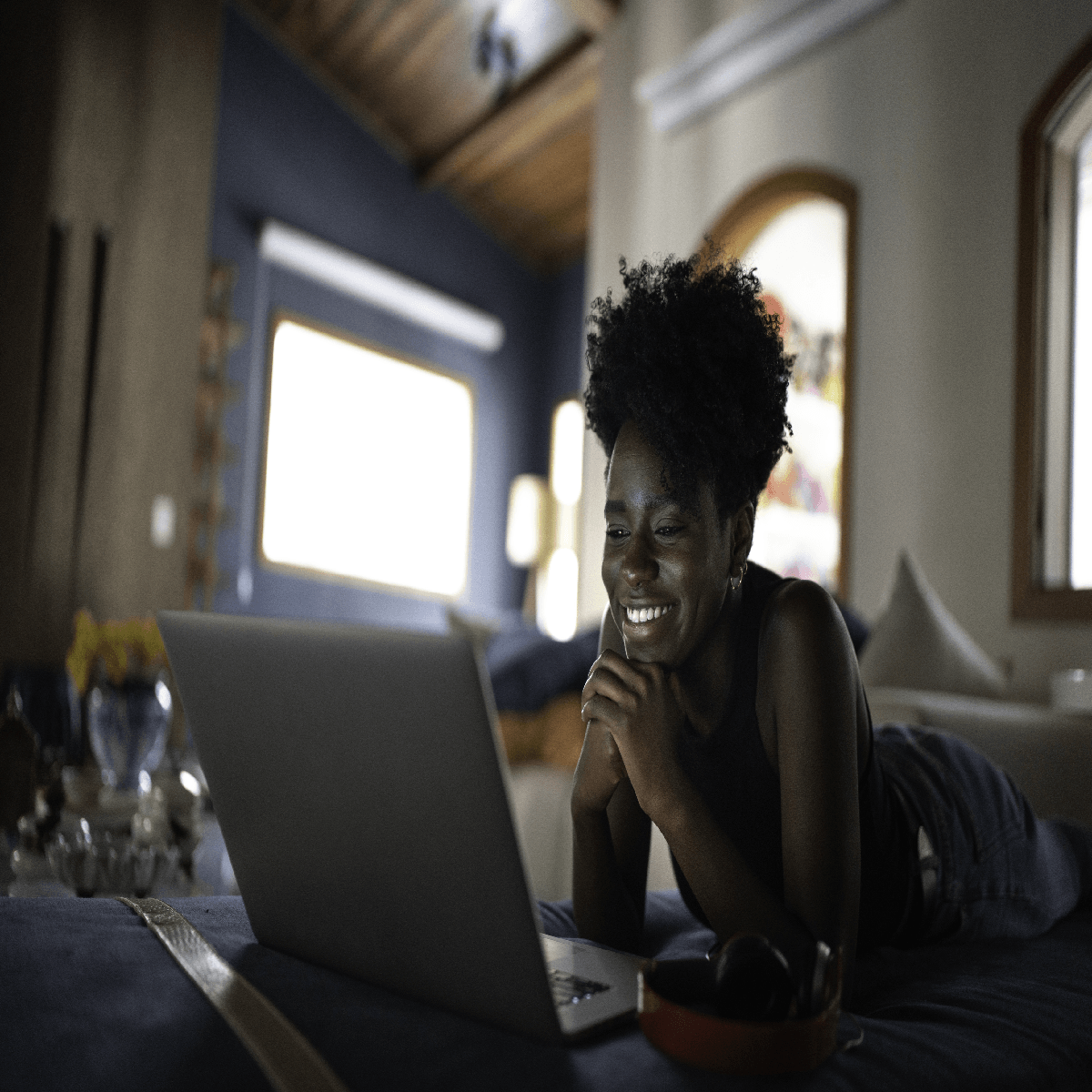 A woman is laying on a couch using a laptop computer