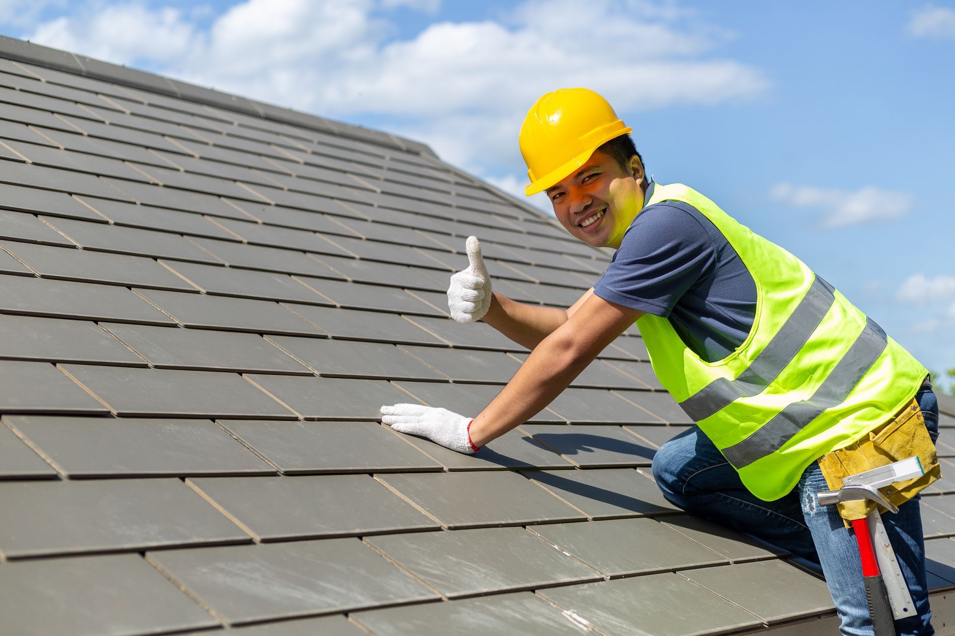 Roofing worker is smiling at the camera with a lifted thumb.