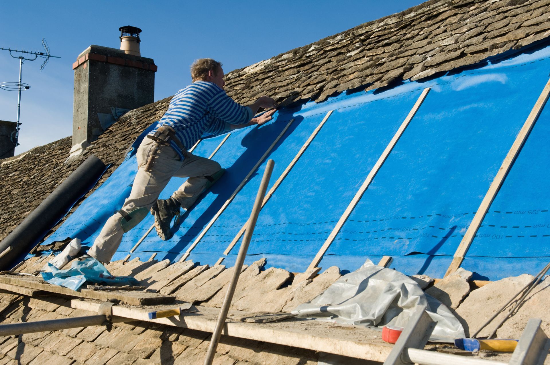 Man tiling a roof with slate rock.