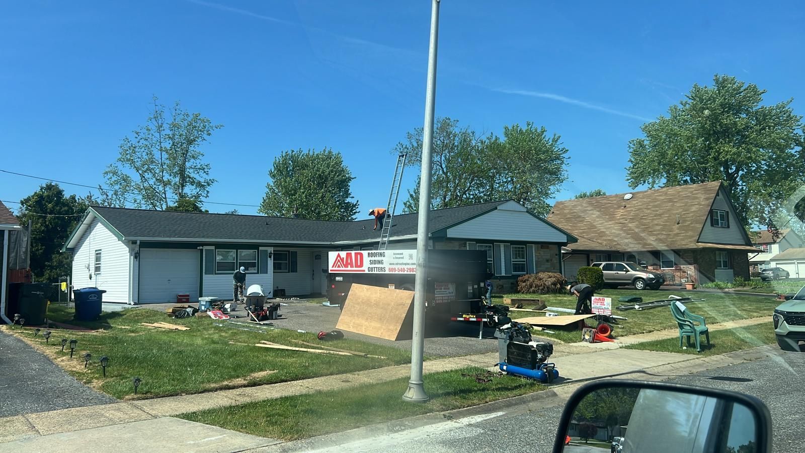 A Car Is Driving Past a House That Is Being Remodeled — Burlington, NJ — AD Roofer Siding & Gutters