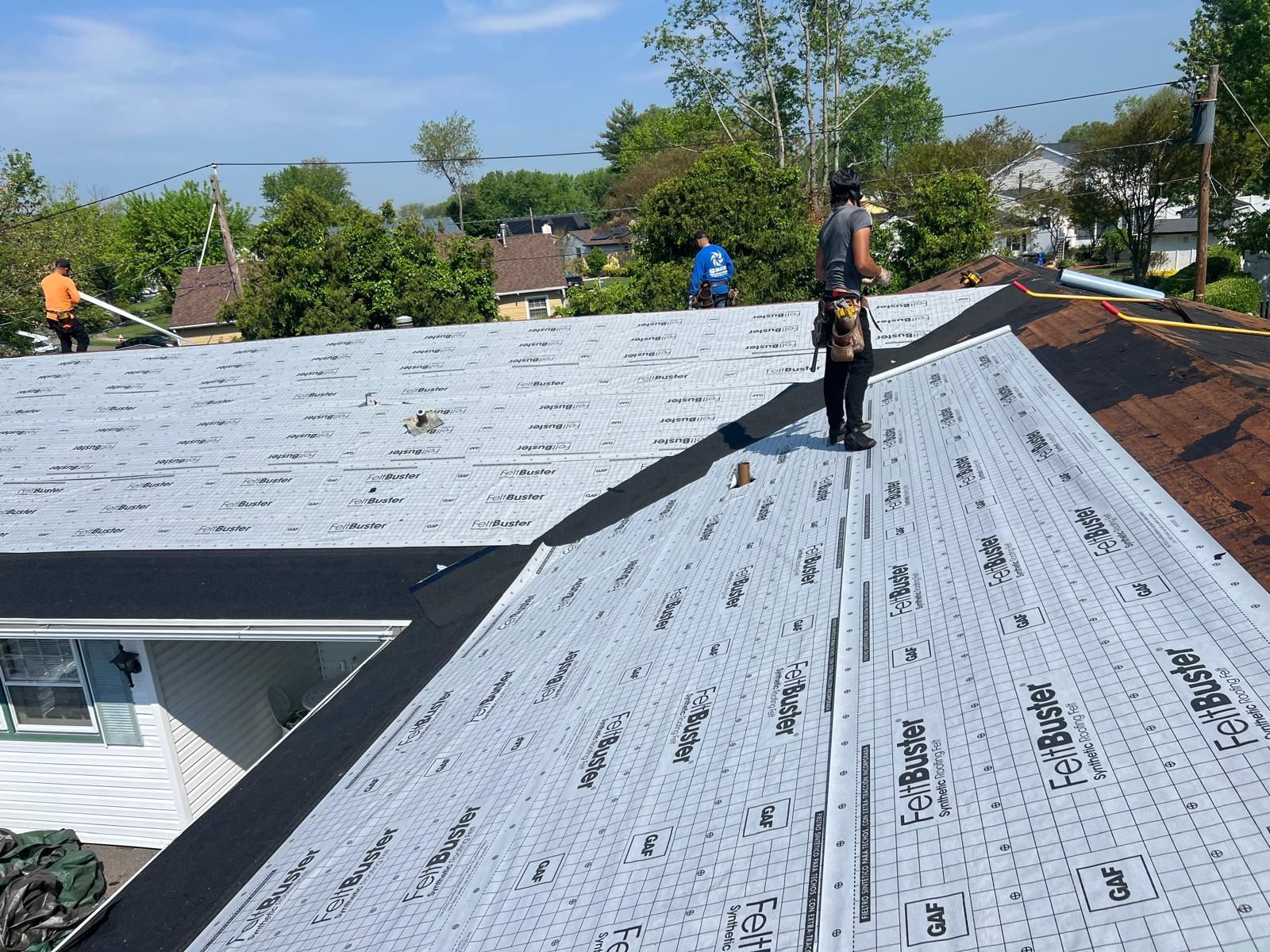 A Man Is Standing on the Roof of a House — Burlington, NJ — AD Roofer Siding & Gutters