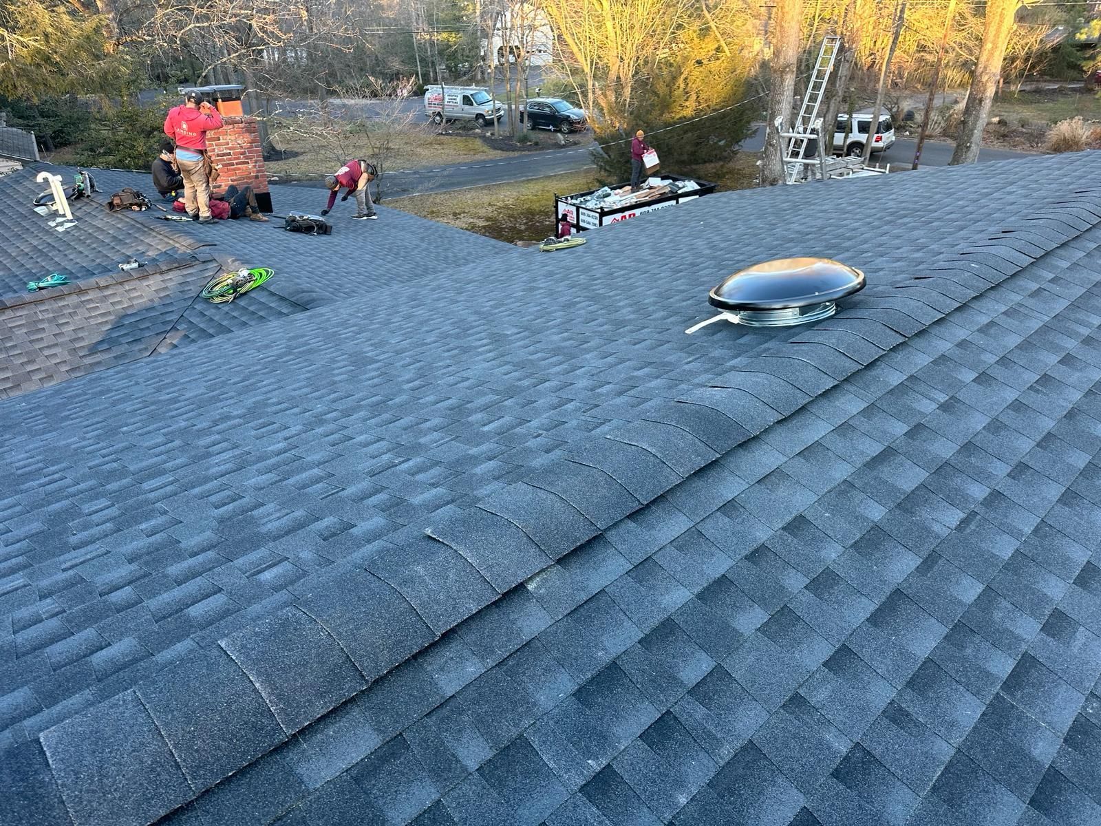 A Group of People Are Working on a Roof With a Chimney — Burlington, NJ — AD Roofer Siding & Gutters