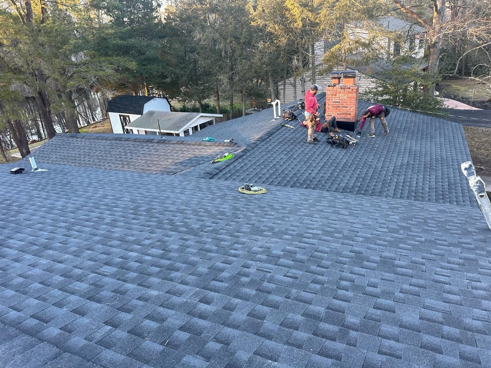 A Group of People Are Working on the Roof of a House — Burlington, NJ — AD Roofer Siding & Gutters