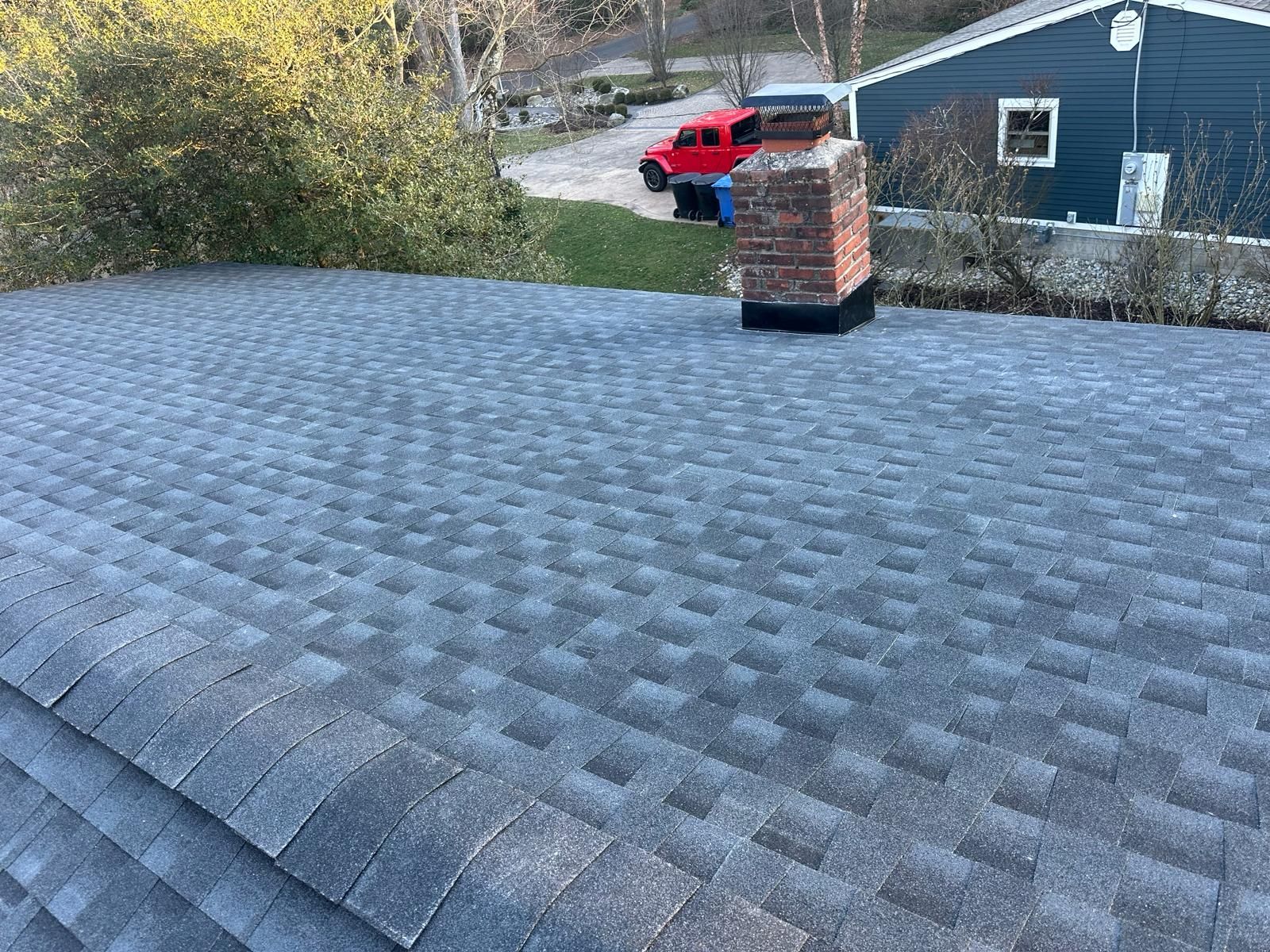 A Roof With a Chimney on It and a Blue House in the Background — Burlington, NJ — AD Roofer Siding & Gutters