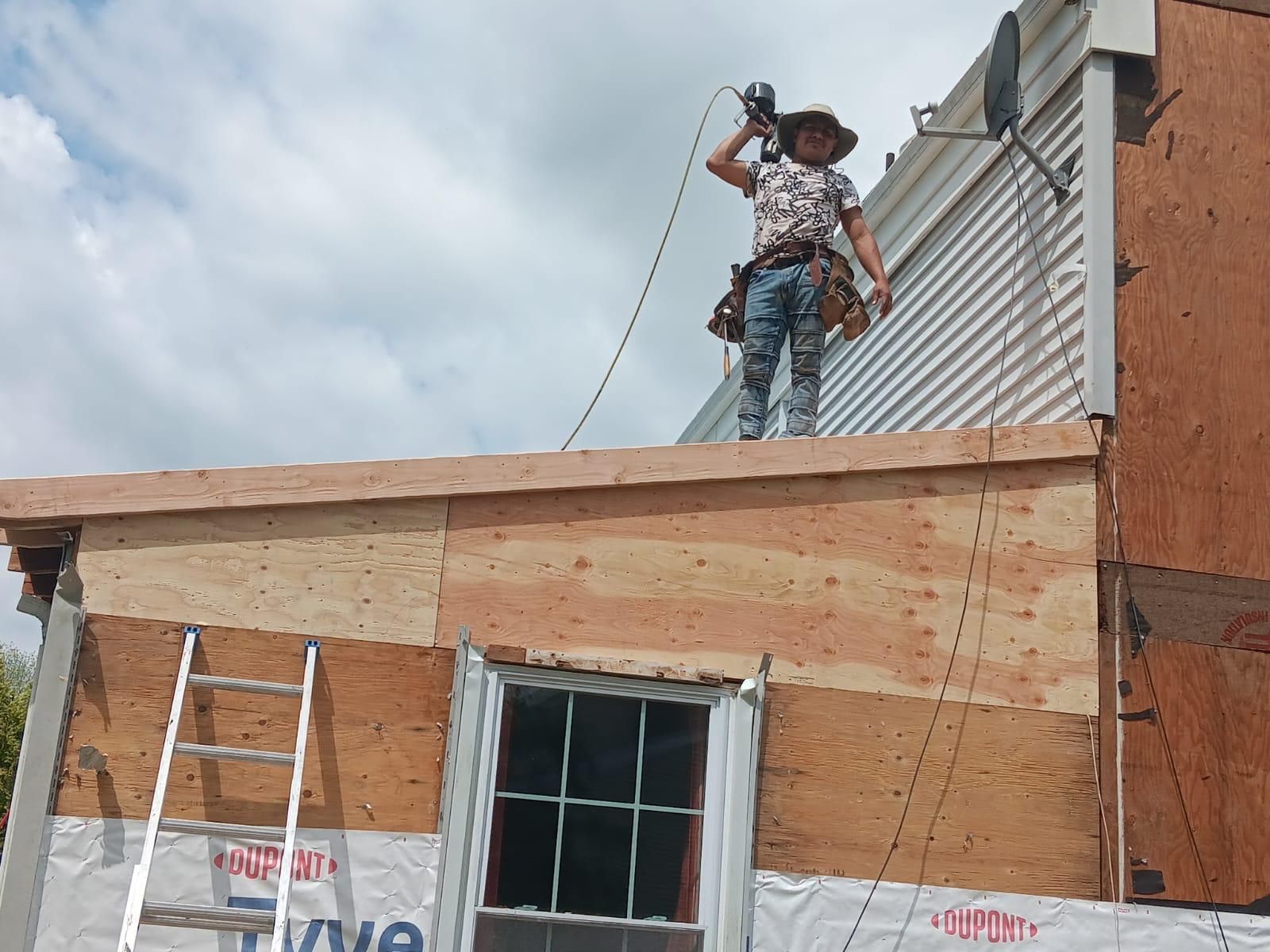 A Man Is Standing on the Roof of a House — Burlington, NJ — AD Roofer Siding & Gutters