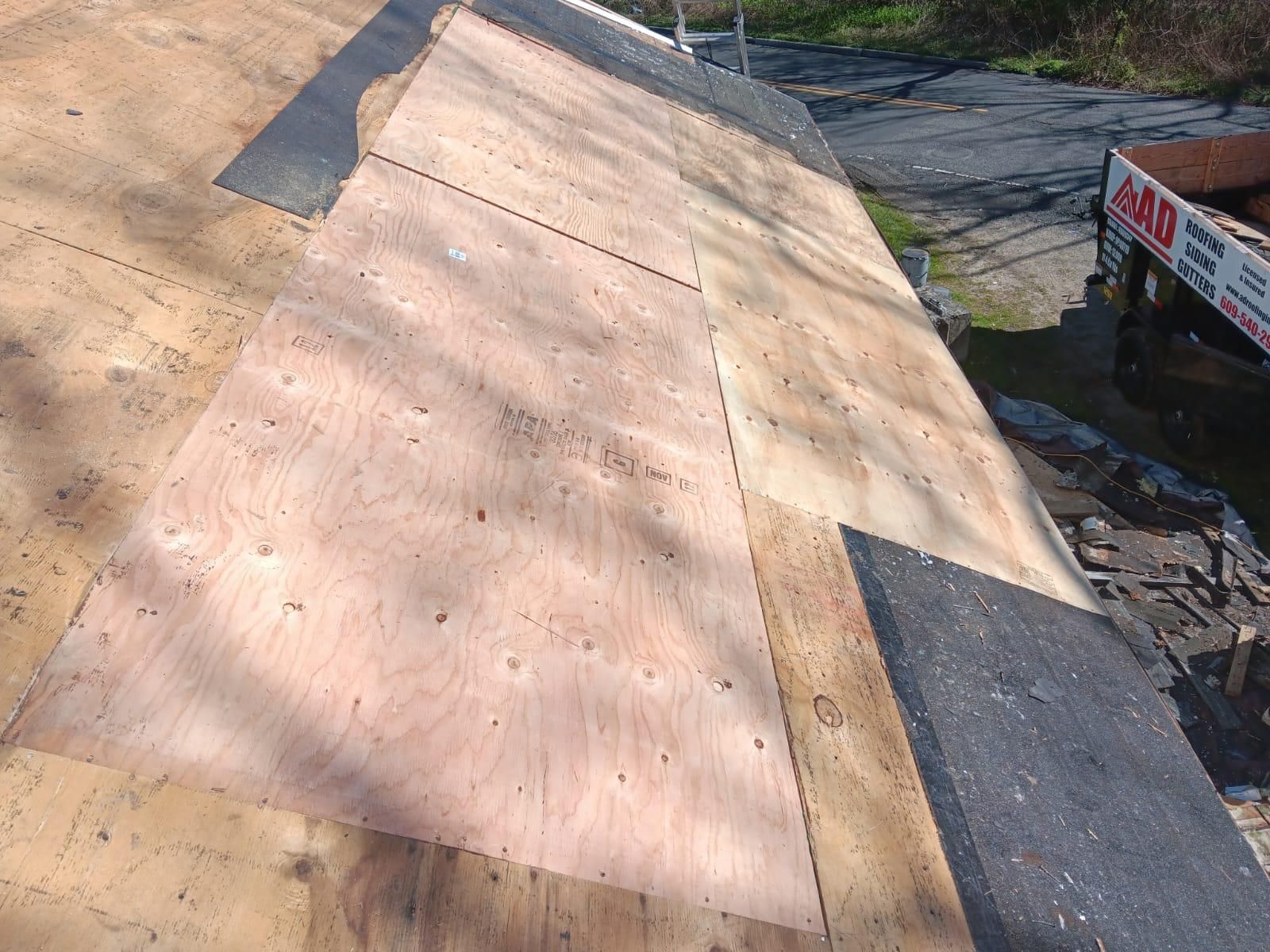 A Piece of Plywood Is Sitting on Top of a Roof — Burlington, NJ — AD Roofer Siding & Gutters